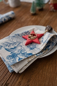 Detail of a Christmas placemat with blue floral patterns on cream linen fabric