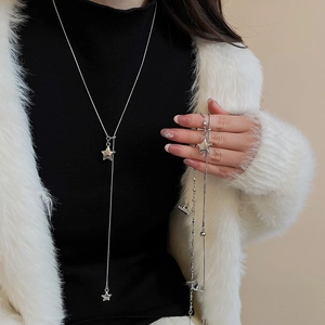 Close-up of minimalist silver star pendant necklace styled on a black turtleneck sweater