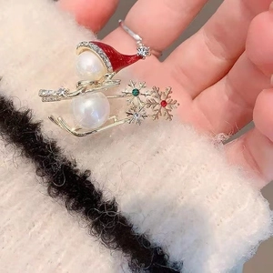 Detail of pearl snowman brooch on golden sled with rhinestones and enamel hat