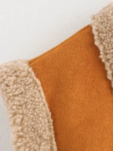 Detail of brown faux suede fabric with soft beige faux fur trim on a sleeveless vest
