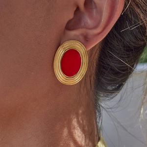 Elegant gold oval earrings with red stone inlay shown on model for a luxury style