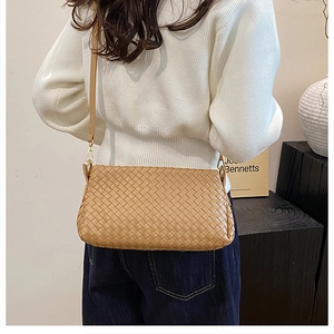 Détail du sac en cuir tressé kaki et des crochets métalliques dorés sur la bandoulière