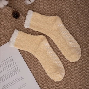Detail showing non-slip silicone grippers on yellow coral fleece slipper socks for women