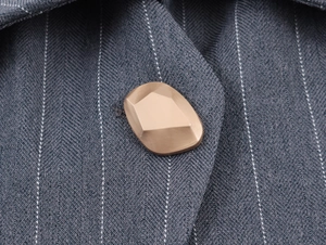 Macro d'un bouton doré facetté sur un gilet gris à rayures avec une texture de tissu fine