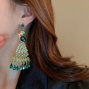Detailed close-up of crystal peacock tassel earring on model showing green teardrops