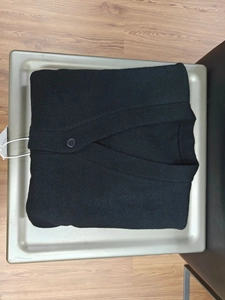 Detail view of the fine knit texture and black resin button on a V-neck cardigan sweater