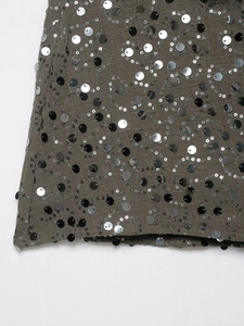 Dettaglio macro di paillettes cucite su tessuto grigio con texture luccicanti