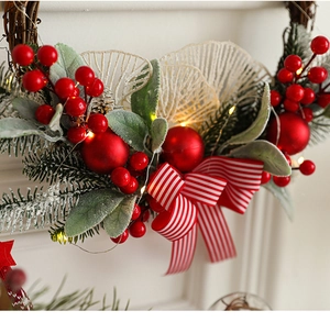 Close-up of Christmas wreath with red berries, pine needles, and a striped ribbon bow