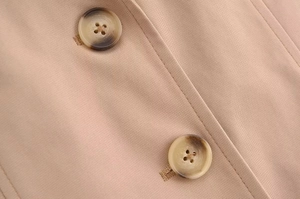 Detailed macro view of khaki twill fabric texture and tortoise resin buttons on a blazer