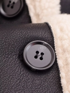 Detailed macro view of black faux leather texture with white faux fur lining and matte button