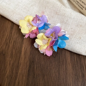 Macro shot of colorful chiffon flower earrings with multiple textile layers on fabric