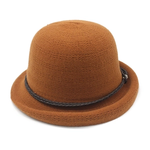 Detail of a brown knitted sun hat with a dark braided band and metal buckle accent