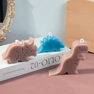 Drie schattige dinosaurusgeurkaarsen in pastelkleuren op boeken voor huisdecoratie