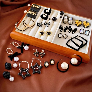 Close-up of black velvet heart earrings and pearl studs displayed in a wooden jewelry box