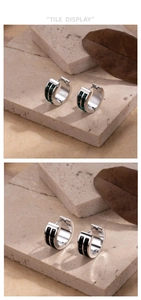 Detail view of double-row emerald green and black stone inlaid stainless steel hoop earrings
