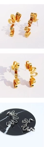 Detailed macro view of gold and silver wavy abstract earrings with architectural design