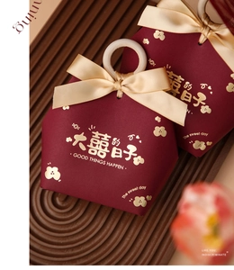 Close-up of hexagonal red candy boxes with gold bow and wooden ring handles