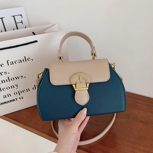 Detail of color-block leather handbag with gold metal buckle and textured finish