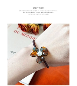 Detail of amber clover hair tie with pearl center worn on wrist for an elegant look