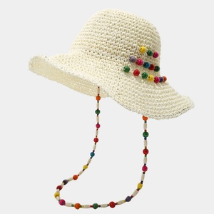 Détail d'un chapeau de paille au crochet avec perles colorées et cordon coupe-vent assorti