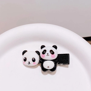 Detail von niedlichen Panda-Haarspangen auf weißem Teller mit schwarzem Stoffbezug