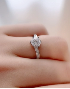 Macro shot of a classic six-prong moissanite ring with side diamonds on a woman's finger