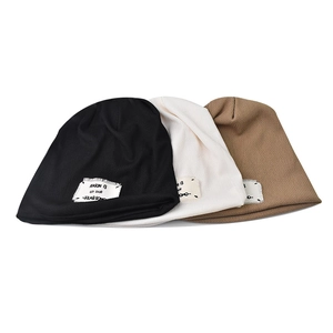 Detailed close-up of ribbed knit beanies in black, cream, and khaki with woven label