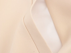 Macro detail of high-quality beige woven fabric texture and stitching on a blazer lapel