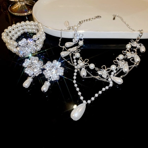 Detailed view of floral diamond drop pearl necklace and earrings set with starburst shine