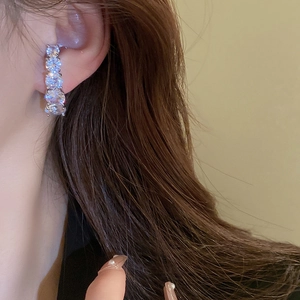 Detailed view of silver needle curved earrings featuring five sparkling round-cut zircons