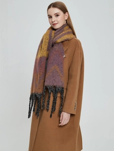 Close-up of thick mohair scarf with wavy pattern and long braided tassels on brown coat