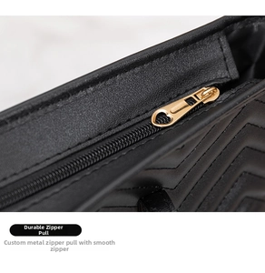 Detail of gold zipper and V-shaped quilted leather on black minimalist tote bag