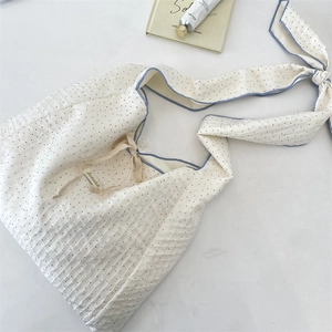 Détail du sac en toile à pois gaufré avec bordure bleue et bandoulière réglable