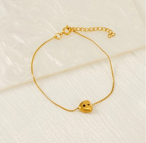 Detail of a thin gold chain bracelet with a 3D heart pendant and adjustable extension