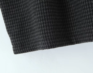 Close-up of high-quality black and grey houndstooth wool fabric on a plaid mini skirt