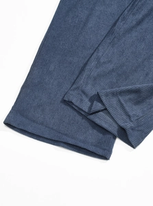 Detailed close-up of dark blue corduroy pants fabric with soft ribbed texture and hem finish