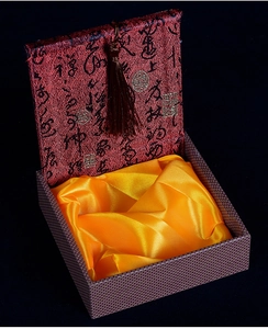Detail of red brocade gift box with gold satin lining and elegant tassel decoration