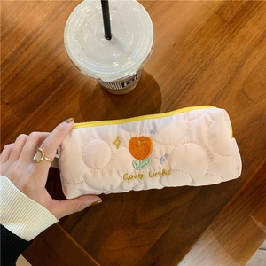 Detailed close-up of pink quilted makeup bag with tulip embroidery and yellow zipper