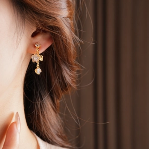Close-up of gold flower tassel earrings with clear gems worn by a female model