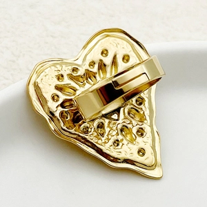Macro detail of the irregular textured back of a gold plated heart ring with polished band