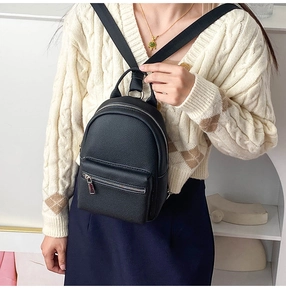 Close-up of a women's black pebble leather mini crossbody bag worn by a model in-studio