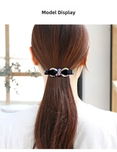 Elegant bow hair clip with acetate pattern and crystal center worn on a ponytail