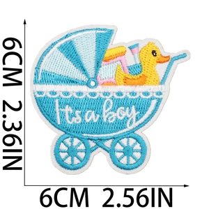 Dettaglio della toppa ricamata con carrozzina blu, testo It's a boy e papera