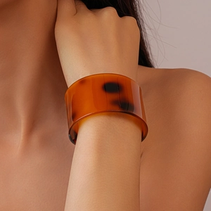 Macro shot of wide tortoiseshell resin bangle showing amber texture and glossy finish