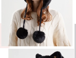 Detail of black faux fur winter hat with large plush pom-poms and long earflap straps