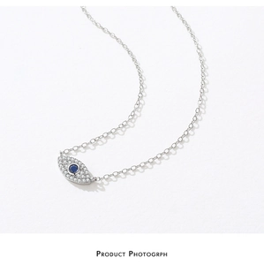 Detailed close-up of a silver Evil Eye pendant with pavé diamonds and a central blue stone
