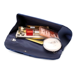 Detail showing the inner capacity of a dark blue satin clutch bag with makeup items