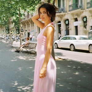 Pink halter neck pleated maxi dress with elegant waist tie shown in sunny outdoor setting
