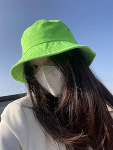 Detail of vibrant green bucket hat made of cotton fabric against a clear blue sky background