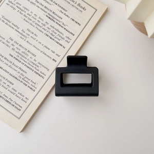 Detailed view of a matte black square hair claw clip placed on an open English book page
